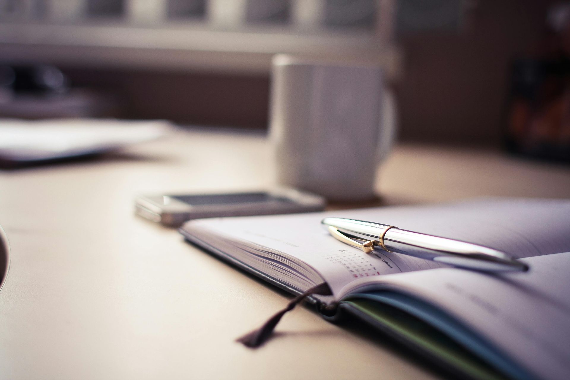 Photo of a diary and a pen on a desk